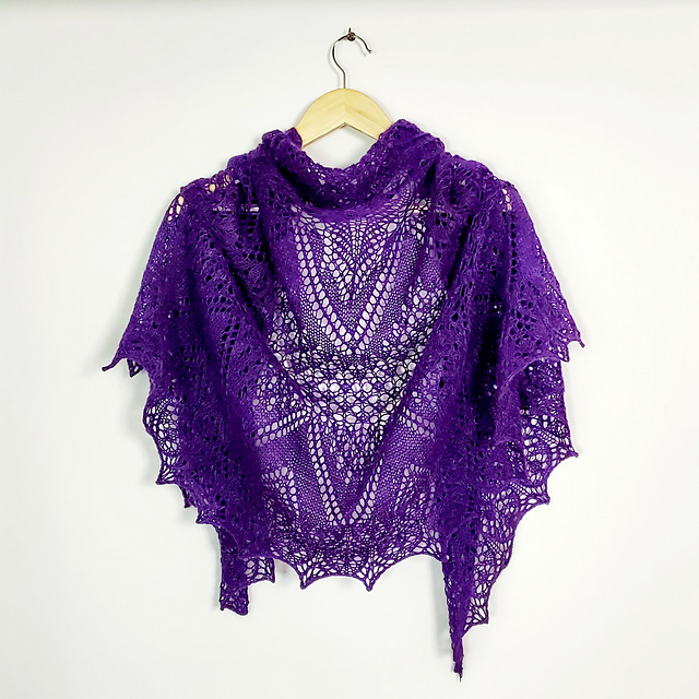 A purple, delicate lace shawl draped over a hanger