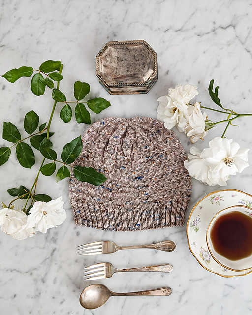 A fitted pink hat with bobble and lace details