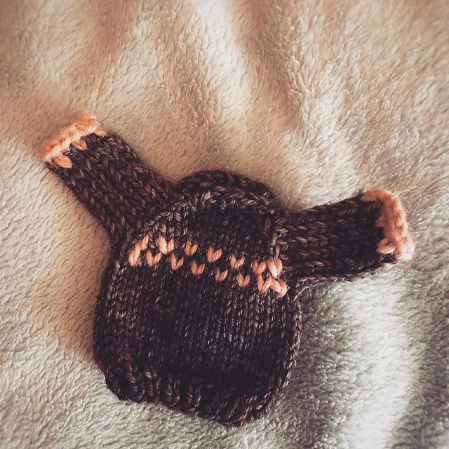 A tiny brown raglan pullover with peach fair isle colorwork across the chest