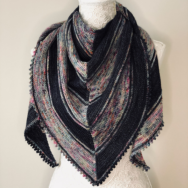 A black and rainbow-variegated striped chevron shawl with picot edge.