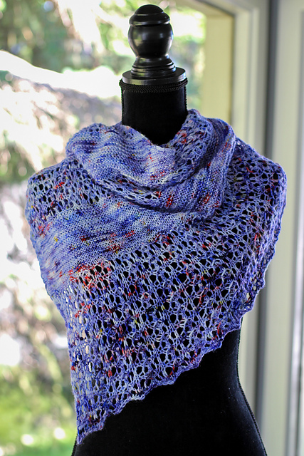 A lace and garter triangle shawl knit in purple yarn with red speckles, displayed on a dress form