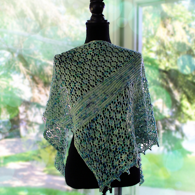 A lace and garter triangle shawl knit in pale green yarn with blue speckles with a picot edge, displayed on a dress form.