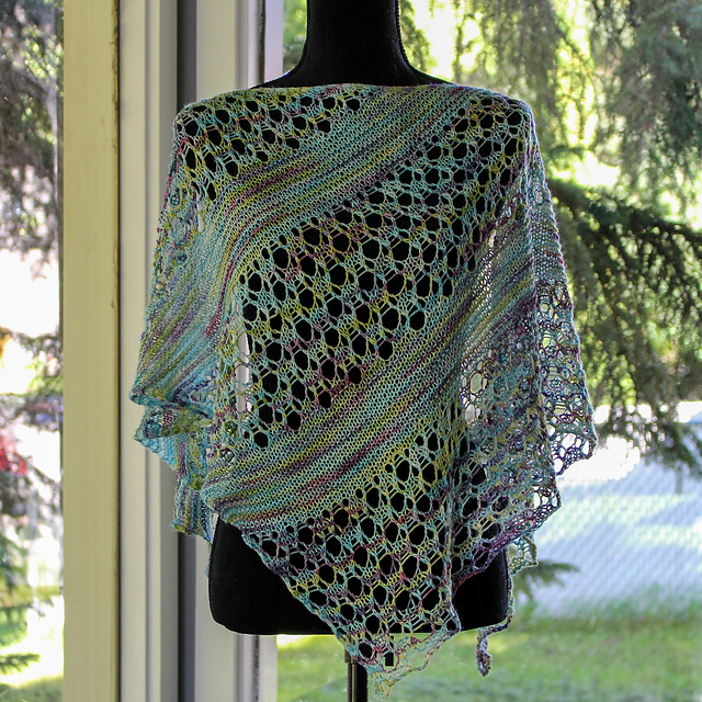 A triangle shawl in variegated aqua, purple, and pale green with sections of garter and large eyelet lace.