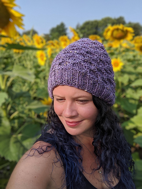 Ashley models a purple tweed knit hat with garter and slip stitches creating a honeycomb pattern.