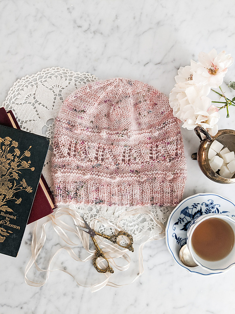 A fitted pink hat with bobble and lace details