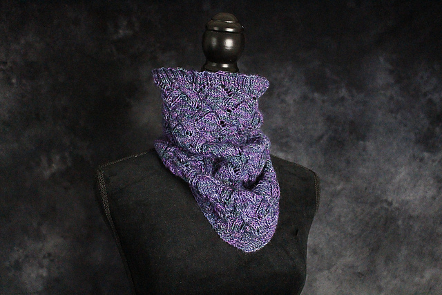 a purple and teal bandana cowl with cables and eyelets, modelled on a dress form