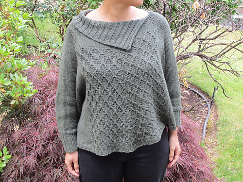 Pullover sweater with a swingy body similar to a poncho. Asymmetrical ribbed collar and diamond designs on the front. Long sleeves with ribbed cuffs.