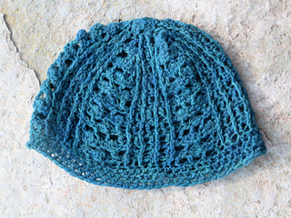 a pair of crochet fingerless mittens laying flat. One mitten is palm up, showing alternating rows of double and single crochet. The other mitten is palm down, showing a lace and bobble crochet pattern on the back of the hand